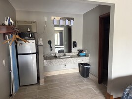 A compact kitchen with a refrigerator, microwave, and a sink with a granite countertop.