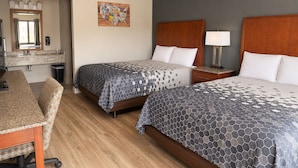 A hotel room with two beds, a desk, a mirror, and a wall art piece. - Econo Lodge Oskaloosa (Oskaloosa)