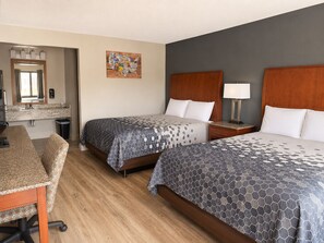 A hotel room with two beds, a desk, a mirror, and a wall art piece. - Econo Lodge Oskaloosa (Oskaloosa)