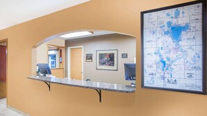 Una zona de recepció amb un taulell, un mapa emmarcat a la paret i una porta que condueix a una altra habitació.