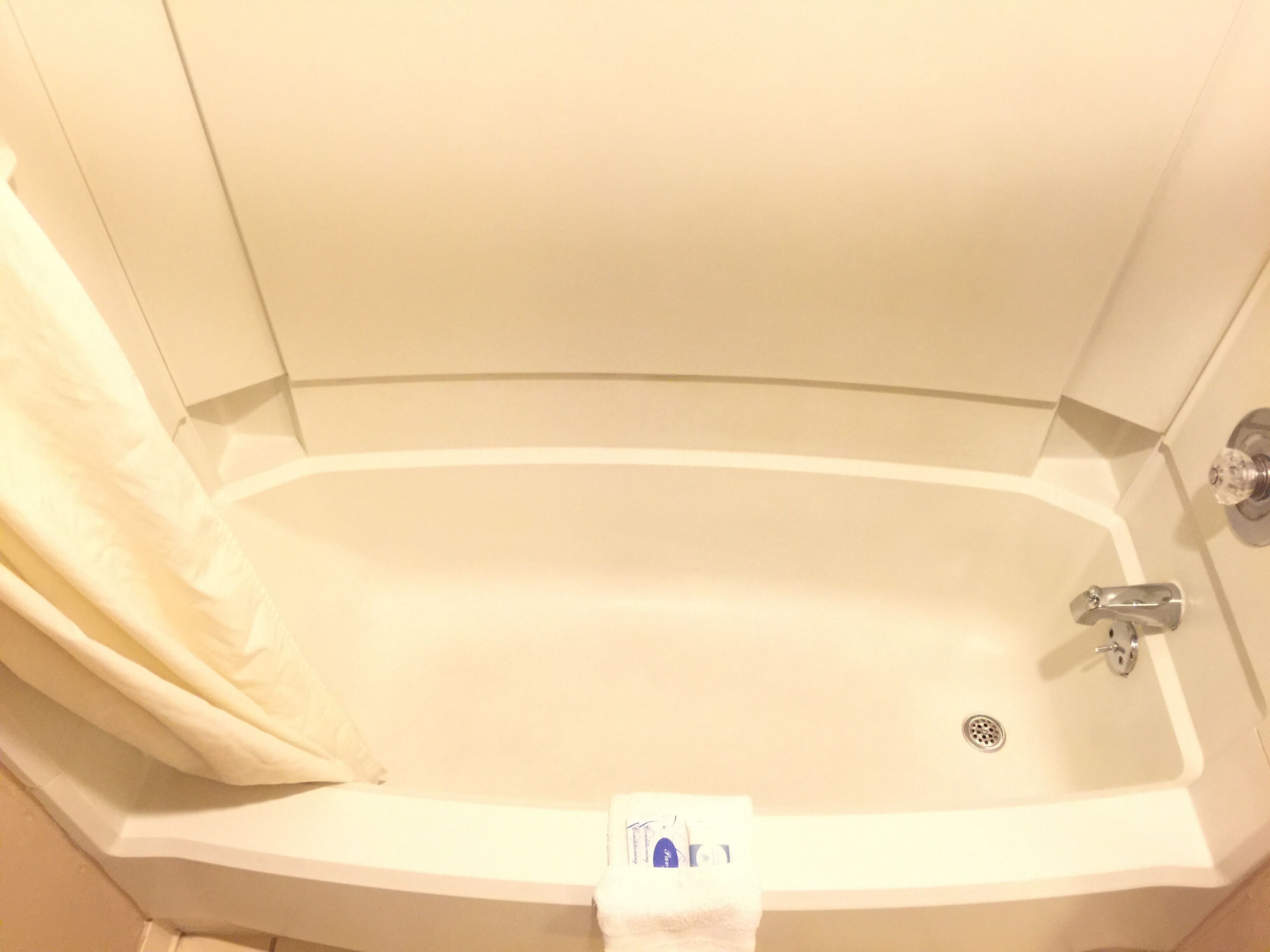 Una bañera con cortina de ducha, una toalla y desagüe.