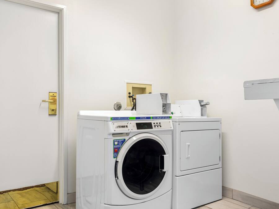 A laundry room with a front-loading washing machine and dryer, a small mirror, and a towel rack.