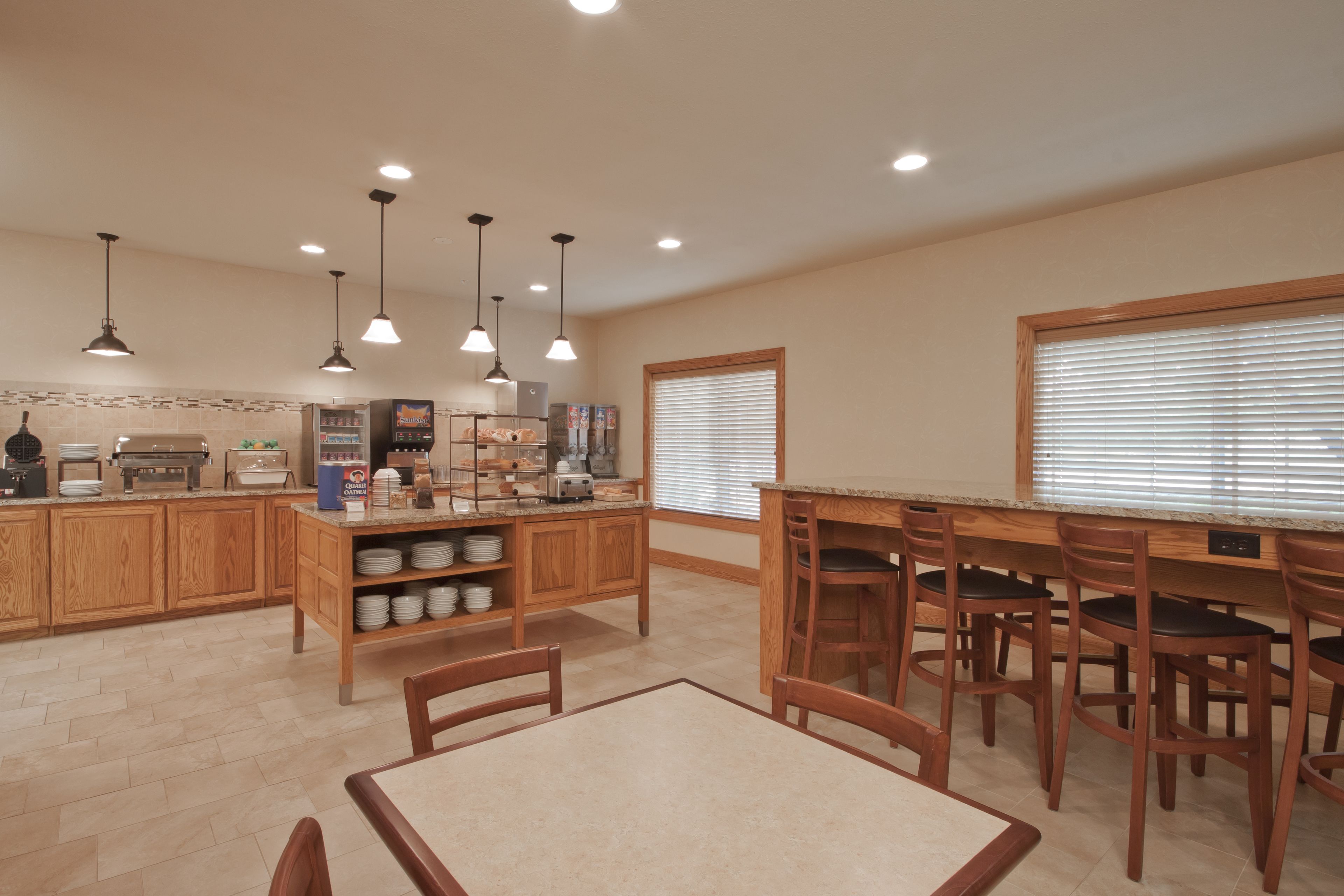 A spacious kitchen with wooden cabinets, a central island with bar stools, and pendant lighting.