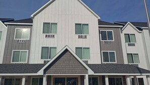 A multi-story residential building with a symmetrical facade, multiple windows with curtains, and a prominent gable roof. - Country Inn & Suites by Radisson, Davenport - Quad Cities (Davenport)