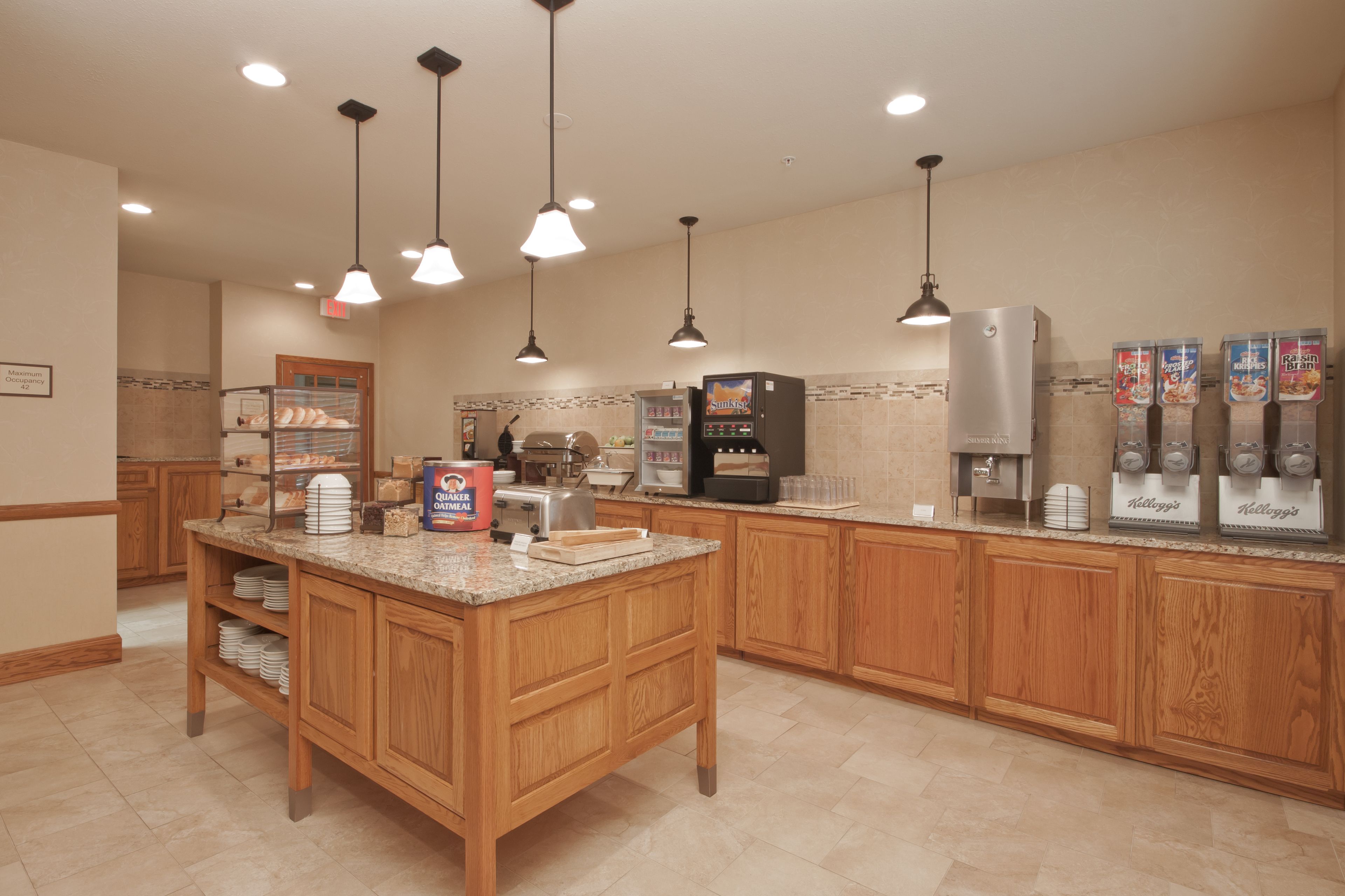 A kitchen with wooden cabinets, a granite countertop, a coffee machine, and a refrigerator.