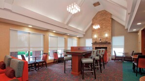 Een hotel lobby met een bar, zitgedeeltes en een open haard.