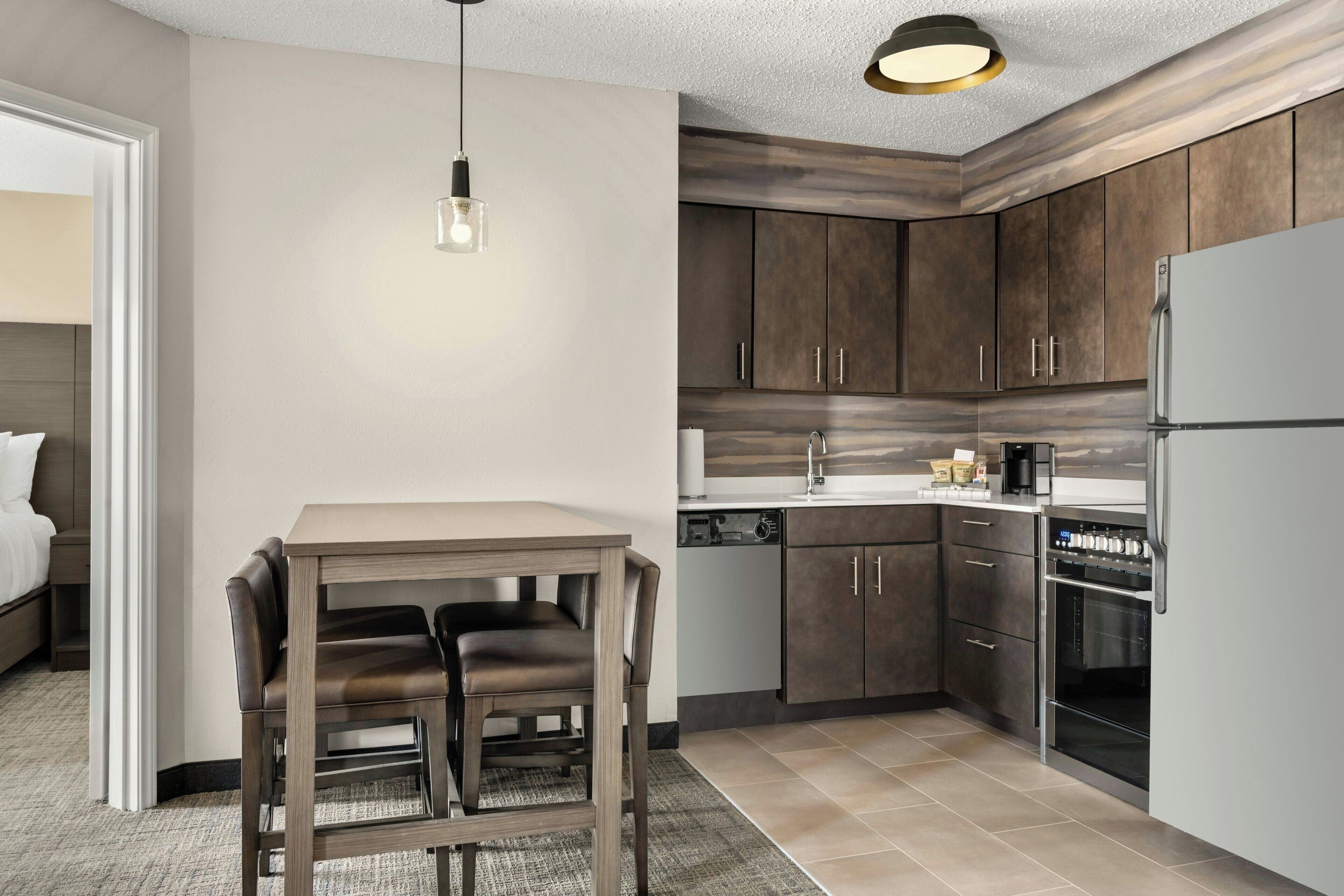 Una cocina moderna con armarios de madera oscura, un refrigerador de acero inoxidable y un horno empotrado.