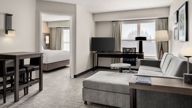 Una habitación de hotel con cama, escritorio con computadora, televisor, sofá y lámpara.