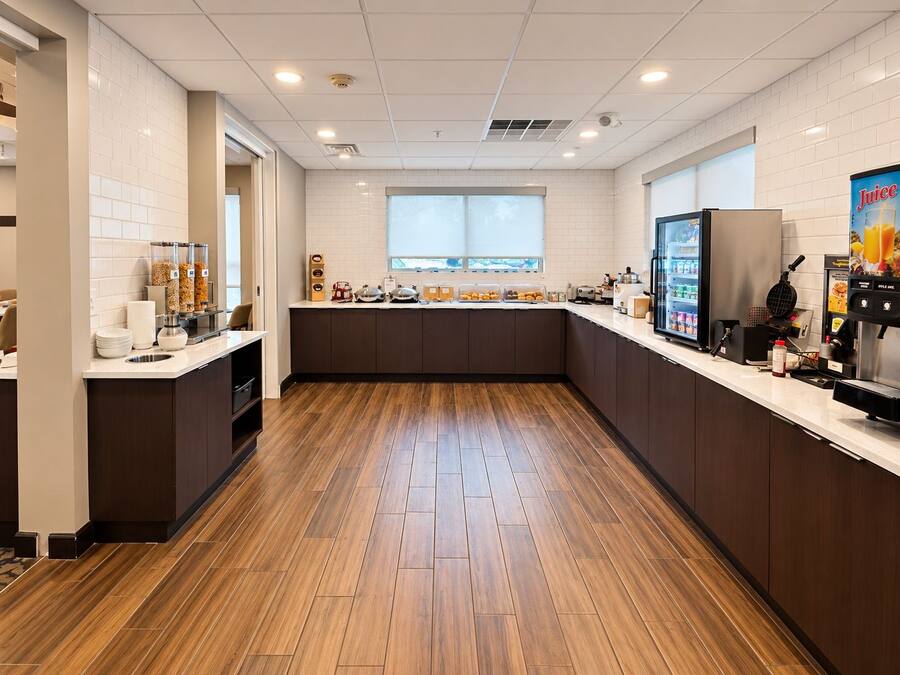 Cozinha moderna com piso de madeira, paredes revestidas de azulejos brancos e uma janela que proporciona iluminação natural.