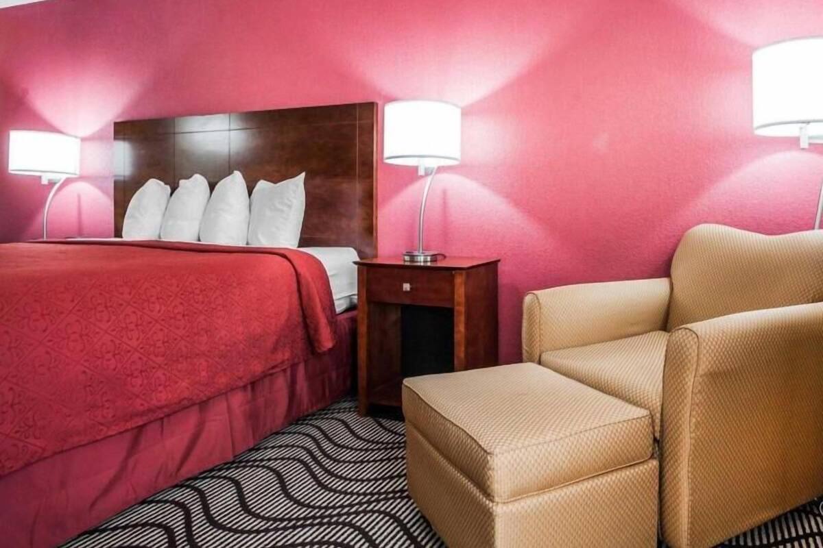 A hotel room with a bed, bedside lamps, a nightstand, and a chair.