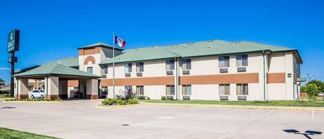 A hotel with a green roof, multiple windows, and a flag.