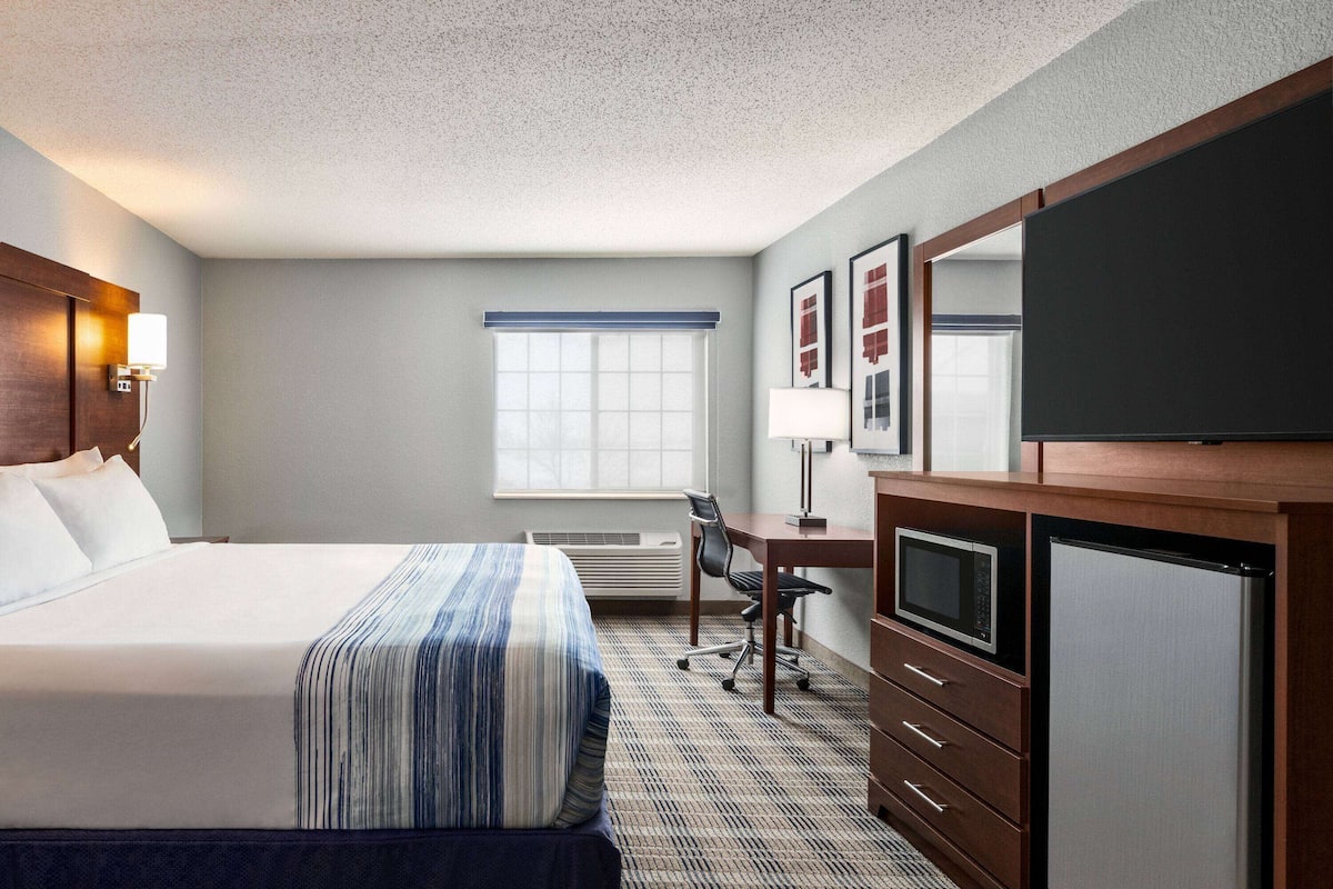 A hotel room with a large bed, a desk with a computer, a television, and a microwave.