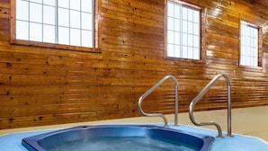 A wooden cabin interior with a hot tub and metal railings. - AmericInn by Wyndham Williamsburg (South Amana)