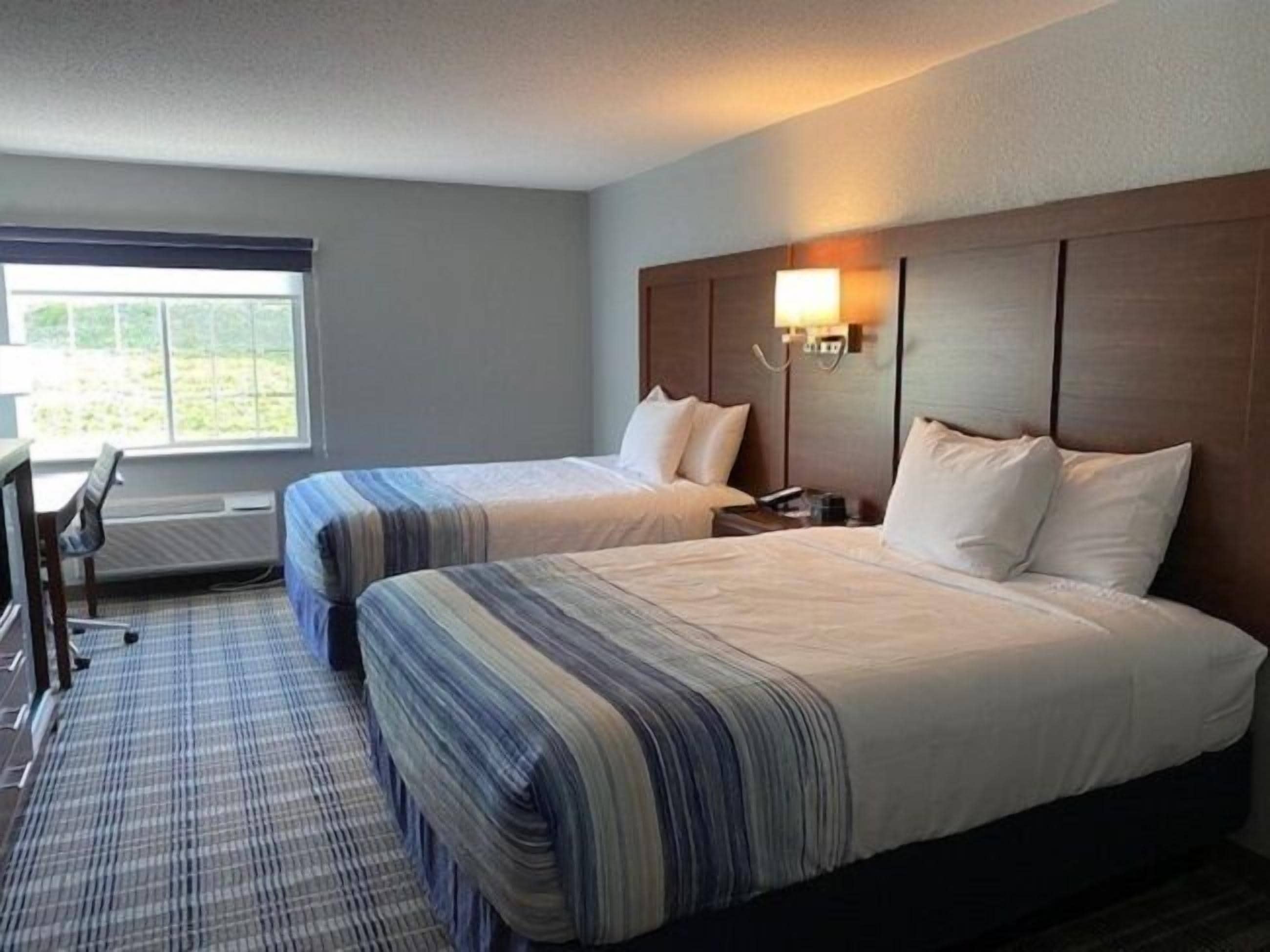 A hotel room with two beds, a desk, and a chair.