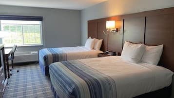 A hotel room with two beds, a desk, and a chair.