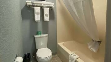 Une salle de bain comprenant des toilettes, une baignoire avec un rideau de douche et un porte-serviettes avec des serviettes.