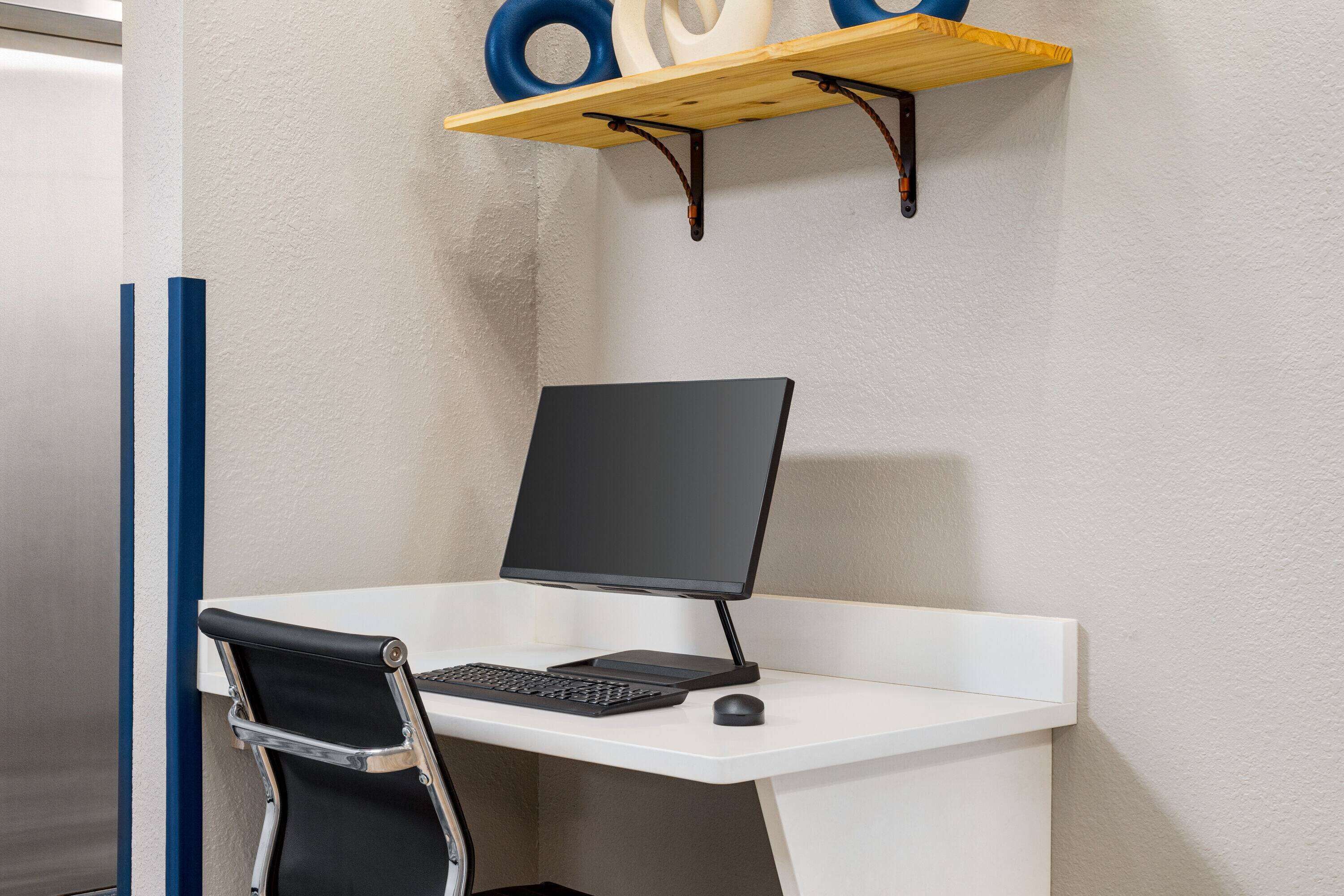 En modern arbetsplats med ett vitt skrivbord, en svart stol och en datoruppsättning.