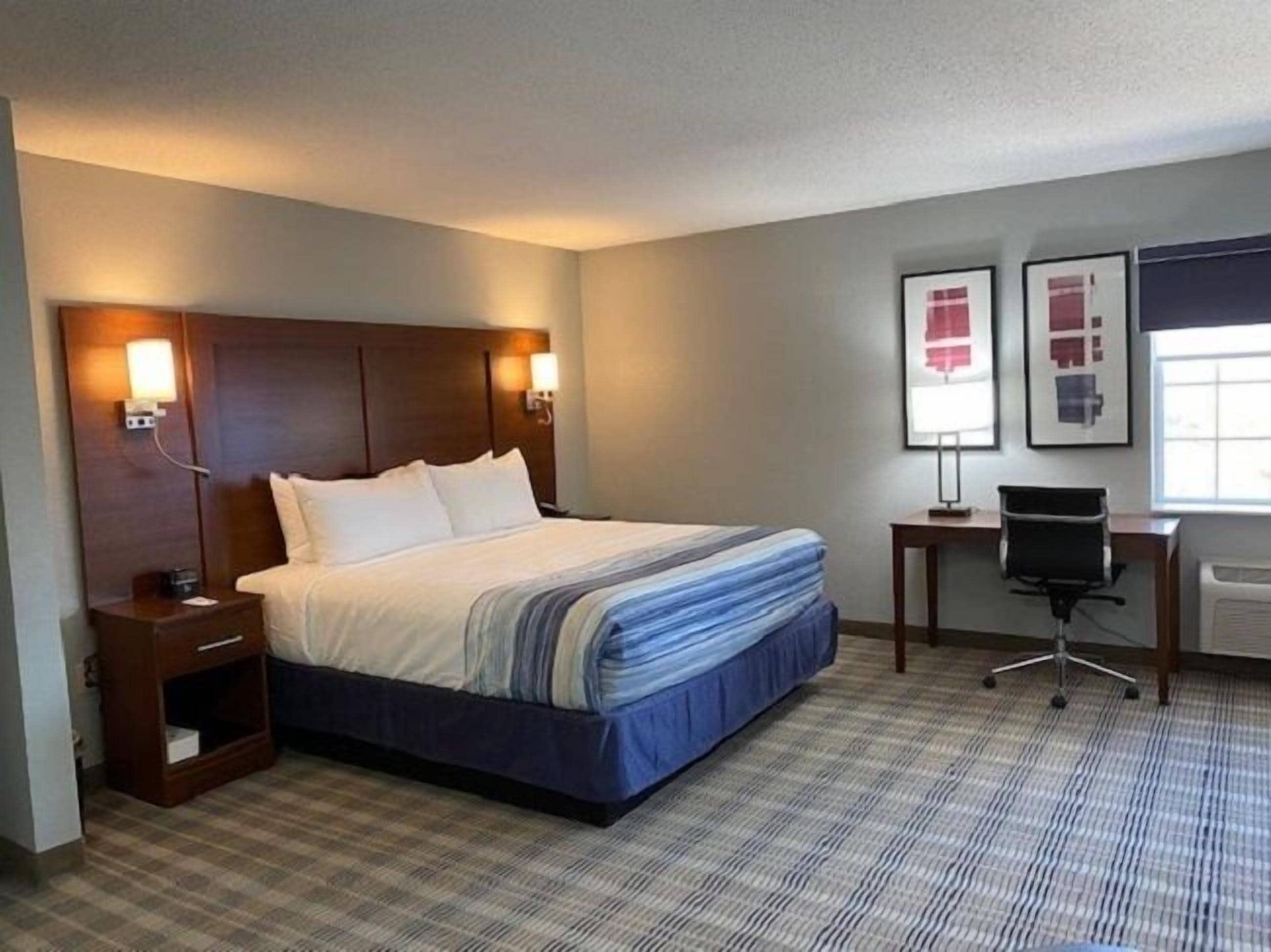 A hotel room with a large bed, bedside tables, a desk, and a chair.