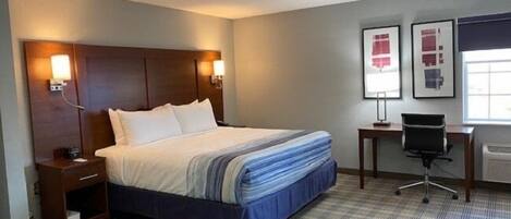 A hotel room with a large bed, bedside tables, a desk, and a chair.