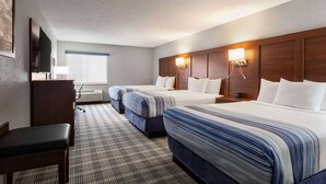 A hotel room with three beds, a desk, a chair, a TV, and a window with blinds. - AmericInn by Wyndham Williamsburg (South Amana)