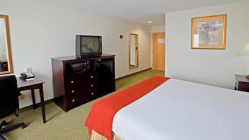 Una habitación de hotel con una cama, un escritorio con teléfono, televisión y espejo.