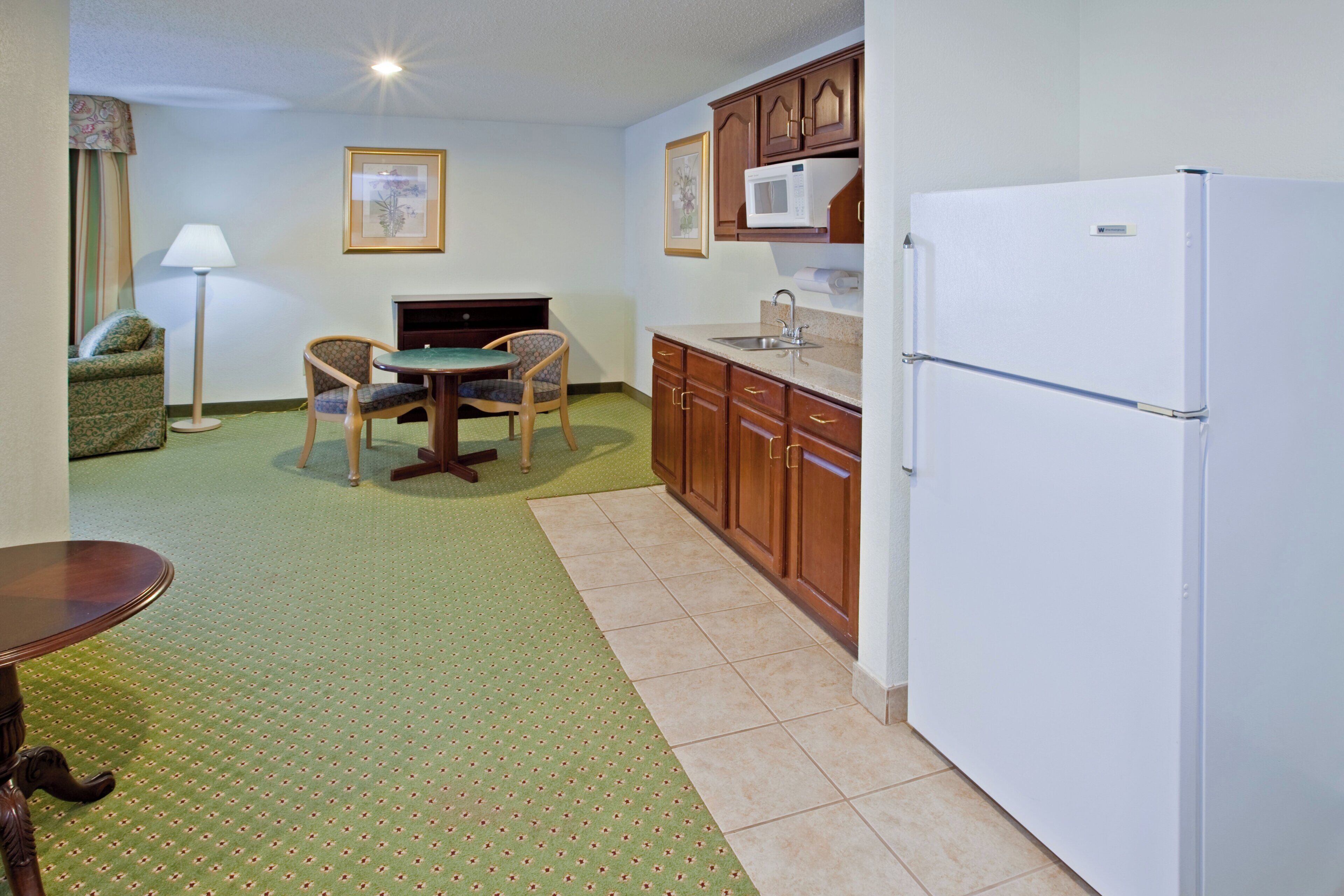 Una cocina compacta con refrigerador, una mesa de comedor con sillas y un mueble pequeño.