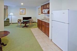 A compact kitchen with a refrigerator, a dining table with chairs, and a small cabinet. - Holiday Inn Express Washington by IHG (Washington)