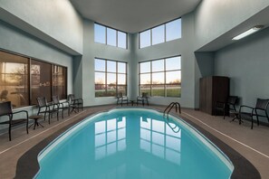 An indoor swimming pool with clear windows, chairs, and a view of the outdoors. - Holiday Inn Express Washington by IHG (Washington)