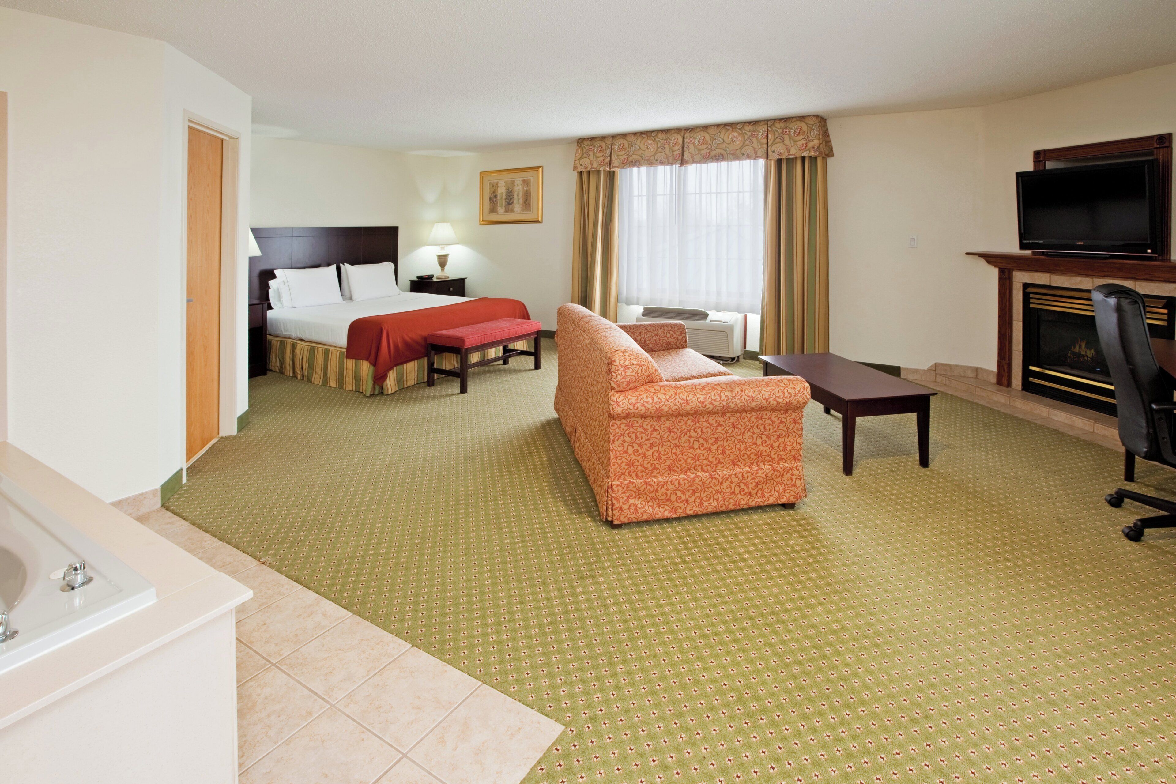 Une chambre d’hôtel équipée d’un lit, d’un canapé, d’un bureau, d’une télévision et d’une cheminée.