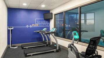 Un gimnasio con cintas de correr, una bicicleta estática y una pared con mensajes motivadores.