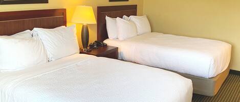 Une chambre d’hôtel avec deux lits, une table de chevet avec une lampe et des tableaux encadrés au mur.