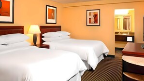 A hotel room with two beds, a nightstand with a lamp, a bathroom mirror, and framed artwork on the walls. - Quality Inn West Lafayette - University Area (West Lafayette)