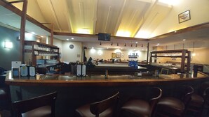 A bar area with a counter, bar stools, and a television screen. - Quality Inn West Lafayette - University Area (West Lafayette)
