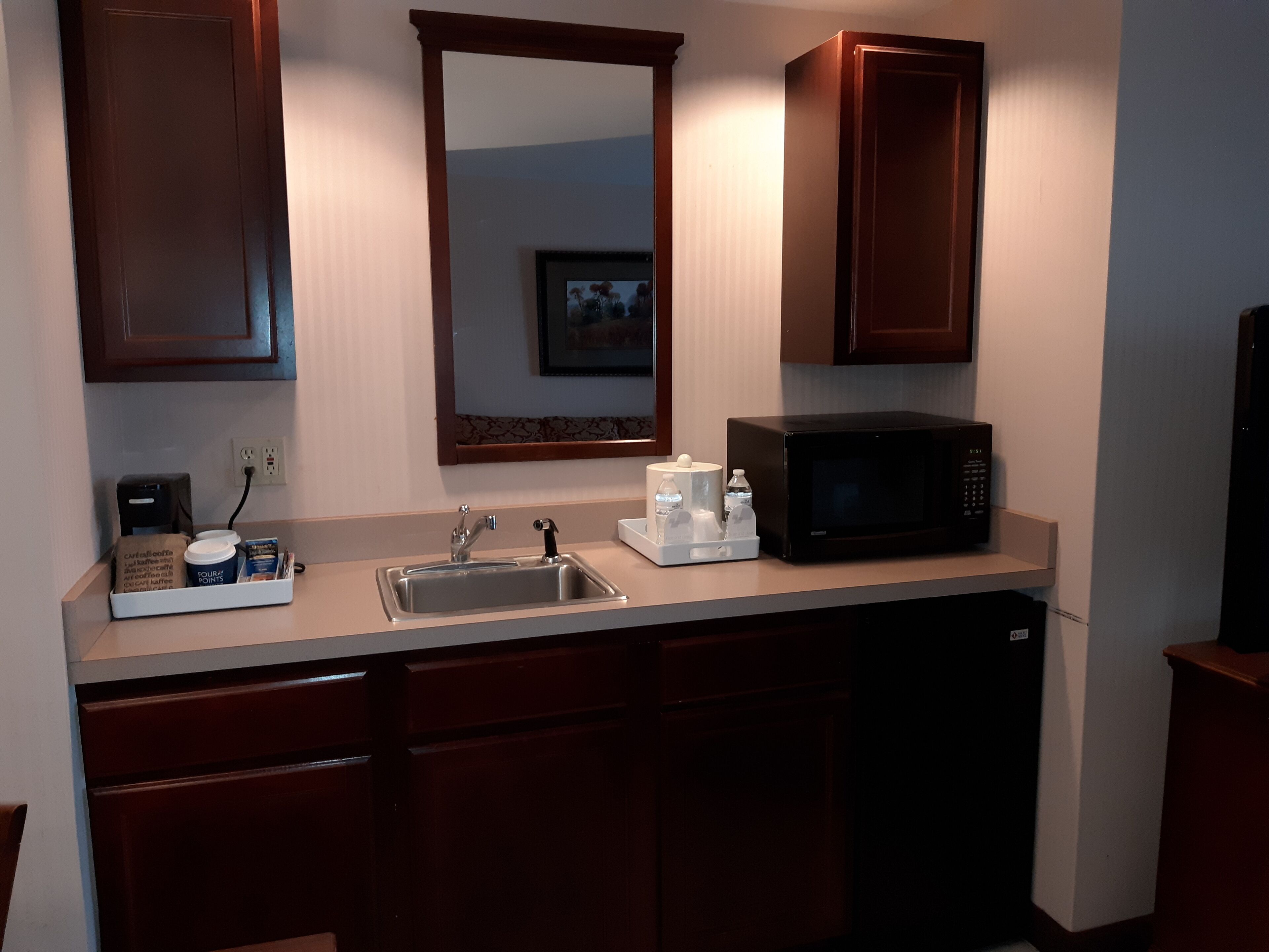 A compact kitchen with a sink, microwave, and coffee maker.