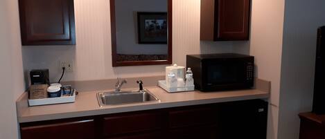 Una cocina compacta con pileta, microondas y cafetera.