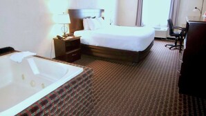 Quarto de hotel com uma cama grande, banheiro privativo com banheira, escrivaninha e uma cadeira.