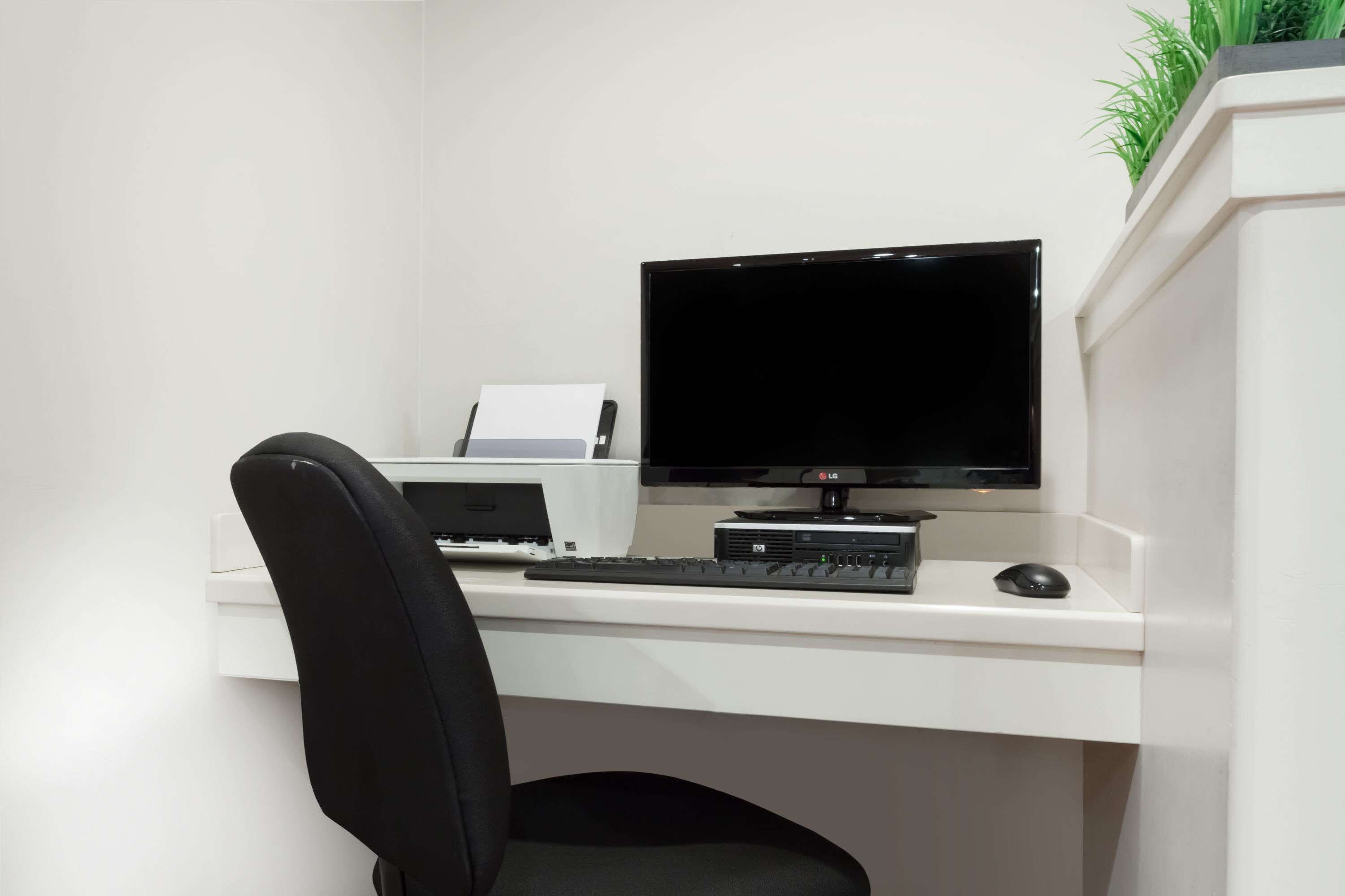 A modern office desk with a computer, keyboard, mouse, and printer.