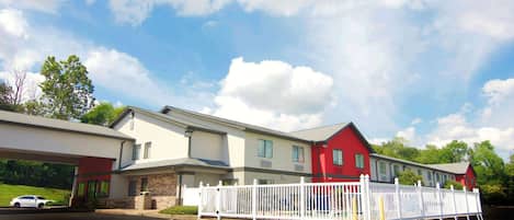 A two-story building with a red and white facade, a covered parking area, and a fenced outdoor space.