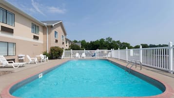 Una piscina al aire libre, sillones reclinables de piscina