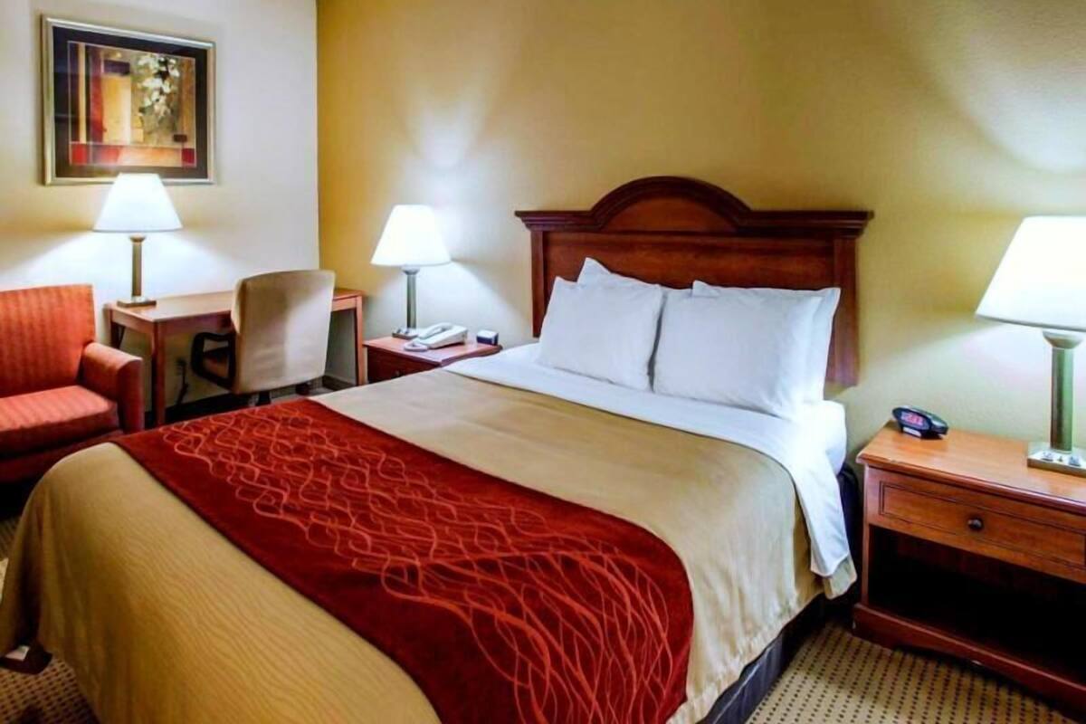 A hotel room with a bed, two bedside tables with lamps, a chair, and a desk.
