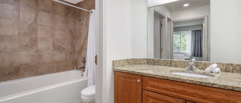 Une salle de bain avec une baignoire, des toilettes et un meuble-lavabo en bois.