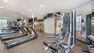 Un gimnasio con cintas de correr, máquinas de pesas y espejos.