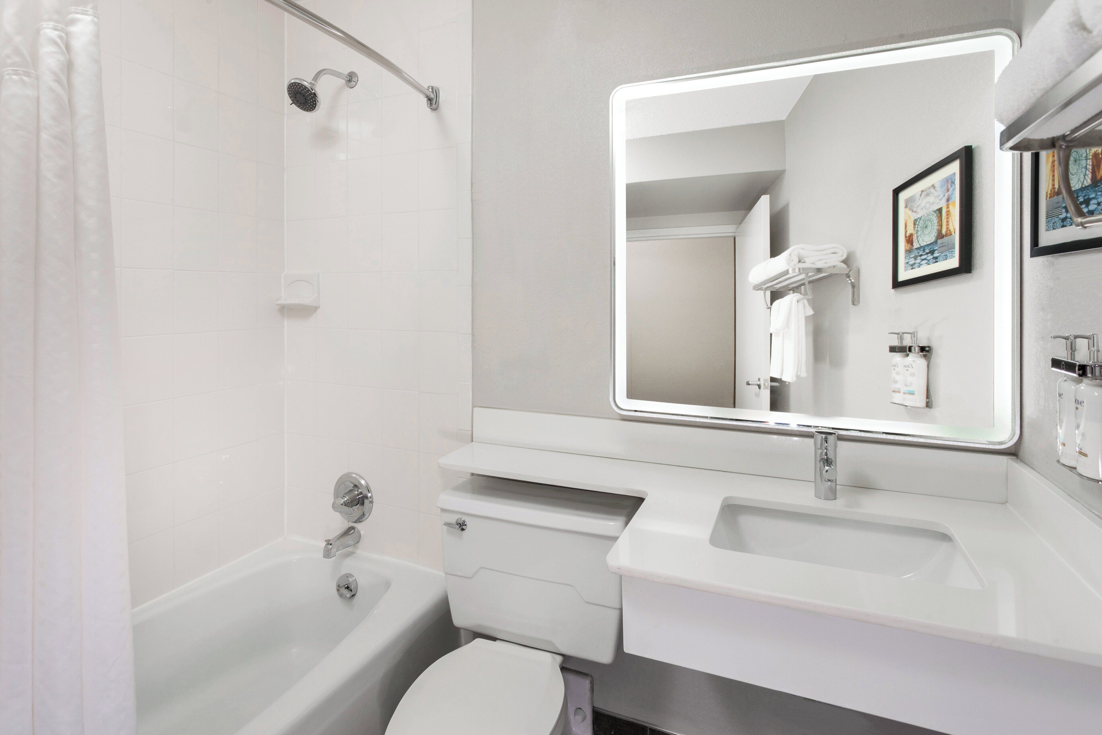 A modern bathroom with a bathtub, toilet, sink, and a large mirror.