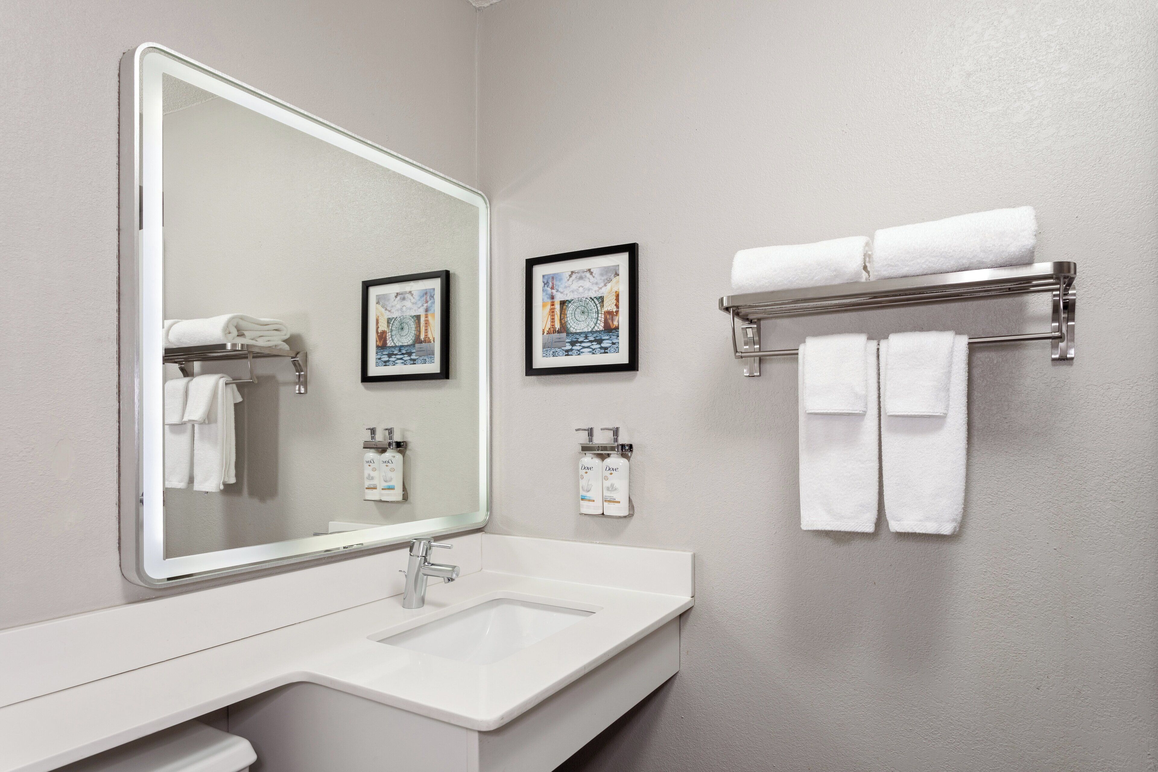 A bathroom with a large mirror, white sink, and towel rack.