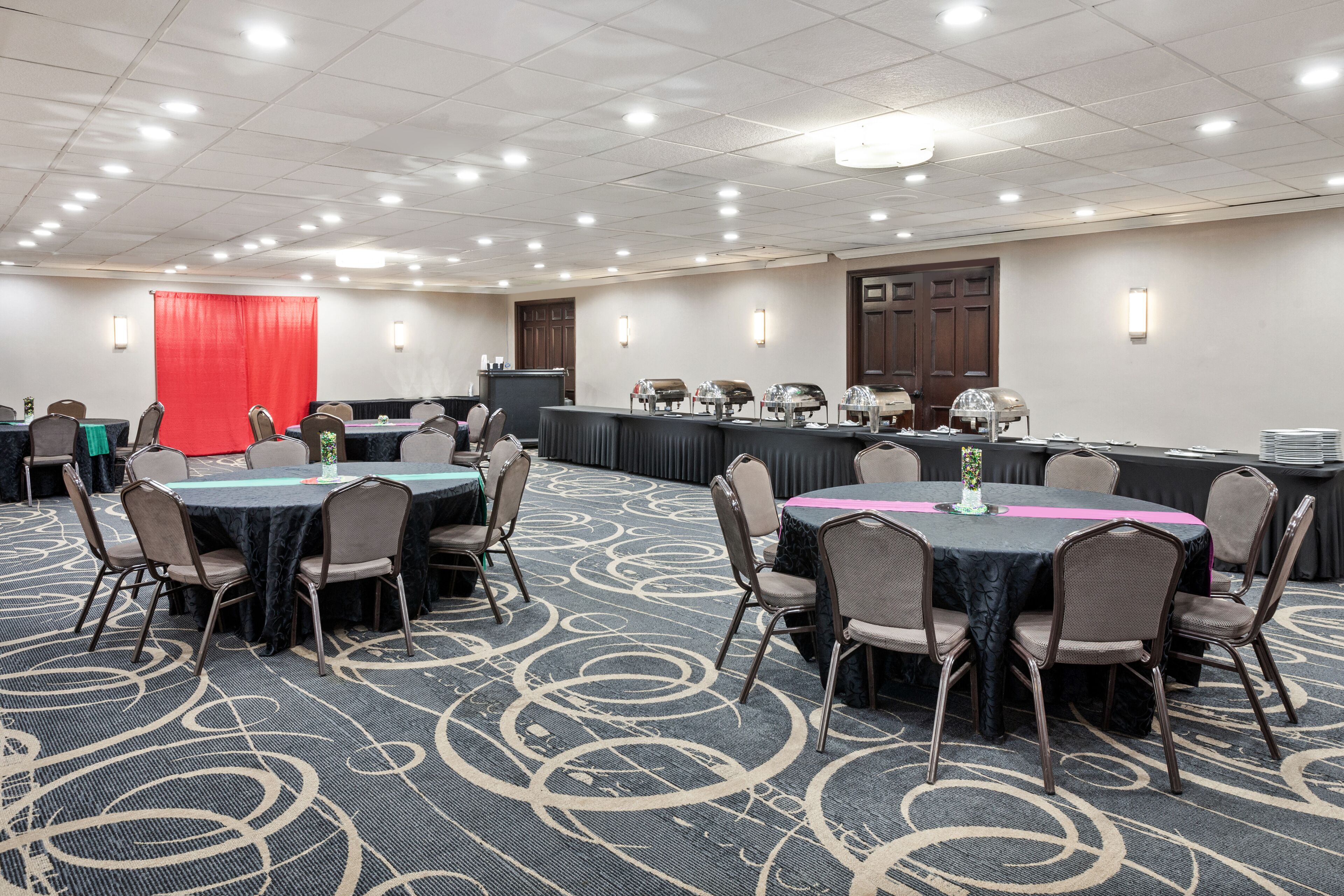 Un salón de conferencias con mesas redondas, sillas y una zona de bufé.