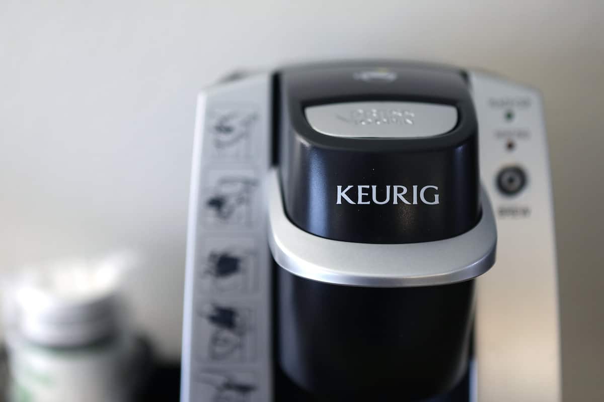 A close-up of a coffee maker with the brand name "KEURIG" visible on the front.