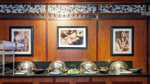 A kitchen counter with three large silver food covers, a framed photograph on the wall, and a tiled backsplash. - Holiday Inn Chicago Oakbrook by IHG (Oakbrook Terrace)