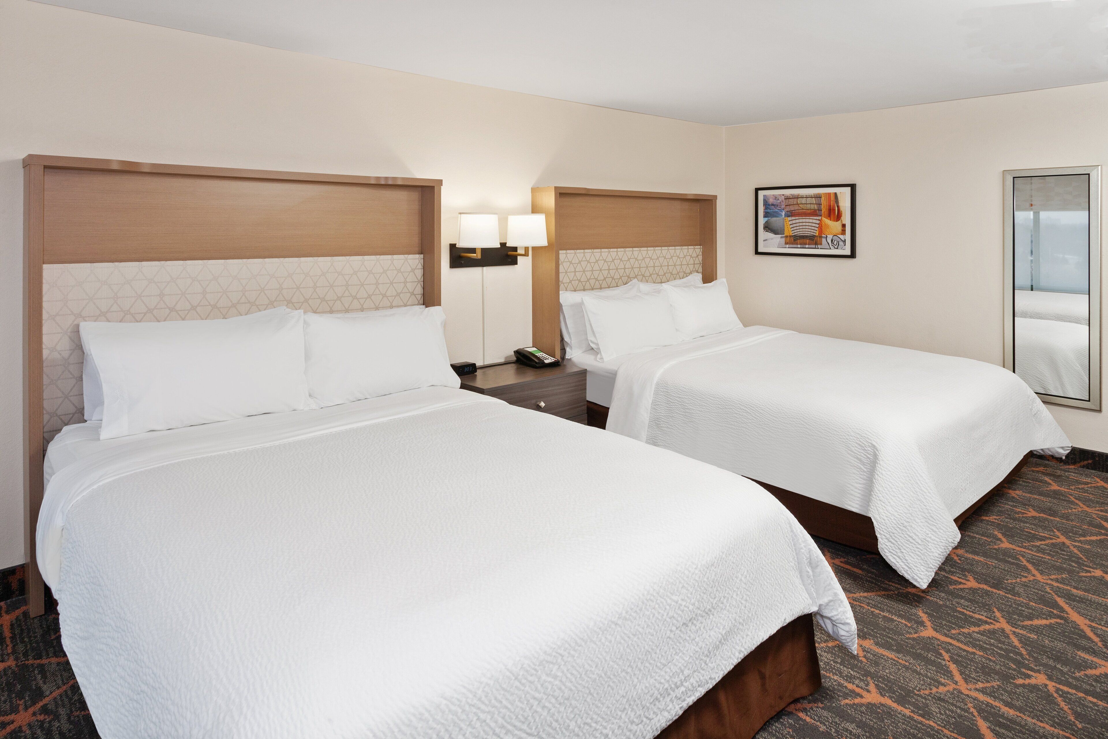 Two single beds with headboards, bedside tables, lamps, and a framed picture on the wall.