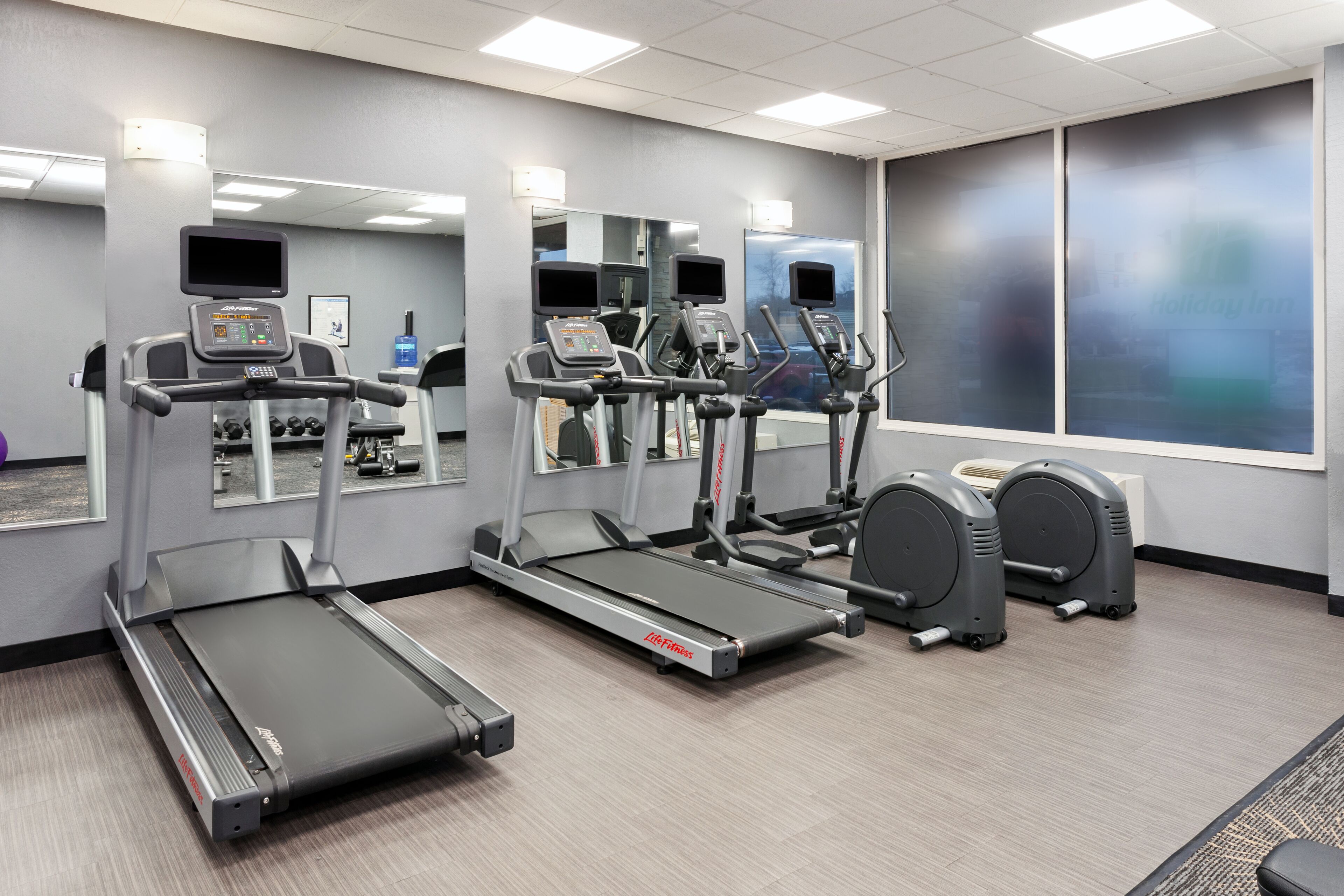 A gym with treadmills, elliptical machines, and weight benches.