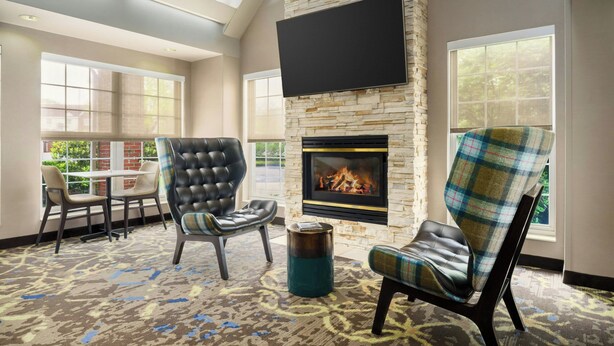 A lounge area with a stone fireplace, comfortable seating, and large windows. - Residence Inn by Marriott Portland Scarborough (Scarborough)